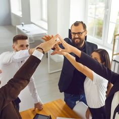 a group of people standing around each other with their hands in the shape of a heart