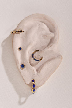 an earring with blue stones on it sitting in a white cloth bag next to a pair of scissors