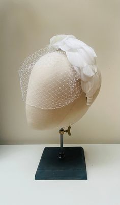 "FABRIC This Women's fascinator headband is carefully hand made. The headband has been covered in luxury white mulberry silk and each feather has been attached within the seams of the fabric headband for a flawless finish. The head crown is light, soft and super comfortable and boasts a quality finish. it also features a beautiful handmade blusher veil with comb fixture. FIT and SIZE A flexible base band to fit all head sizes.  PACKAGING Each headband is wrapped in pretty acid free tissue paper, sealed with an Evierosemade brand sticker and shipped in an eco-friendly cardboard gift box to protect while in transit. If you are purchasing as a gift, please select \"This order is a gift\" (the item price will not be included in the gift box). If you would also like to add a personalised messag Fitted White Headpiece With Handmade Flowers, Adjustable Crown Wedding Costume Headpiece, Adjustable Crown Wedding Headpiece, Fitted Round Crown Headpiece For Weddings, Adjustable Crown Costume Hat For Wedding, Fitted Wedding Headpiece With Round Crown, White Adjustable Hair Accessories For Ceremony, White Adjustable Hair Accessories For Ceremonies, Elegant Wedding Headband Veil