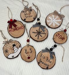 wooden ornaments with snowflakes and sayings are arranged on a white blanket,