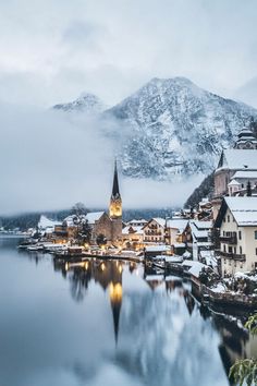 the town is surrounded by snow covered mountains and water with lights on it's buildings