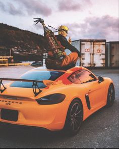 a man sitting on top of an orange sports car