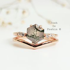 a close up of a ring on a white surface with flowers in the back ground