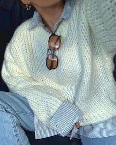 a woman wearing a white sweater and blue jeans