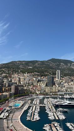 boats are parked in the harbor next to some buildings and hills on a clear day