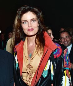 a woman in a leather jacket and hat standing next to other people at an event