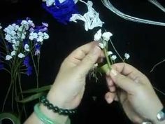 two hands are working on some flowers with beads and bracelets around their wrists, while another hand is holding the flower