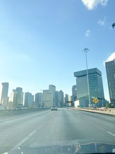 a car driving down an empty highway in front of tall buildings with traffic lights on each side