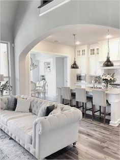 a living room filled with furniture next to a kitchen and dining room table in front of an archway