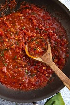 a wooden spoon in a skillet filled with tomato sauce