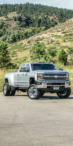 a silver truck is parked on the side of the road in front of some hills