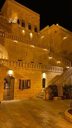 an old building lit up at night with stairs leading to the upper floor and second story