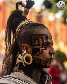 a woman with black face paint and earrings on her head