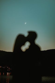 the shadow of a man and woman kissing in front of a moon