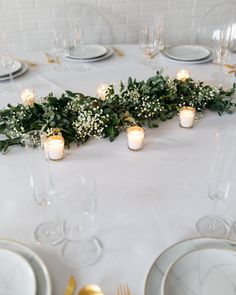 the table is set with candles and greenery for an elegant touch to the place setting