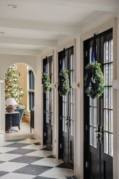 two wreaths hanging on the front doors of a house with black and white checkered floors