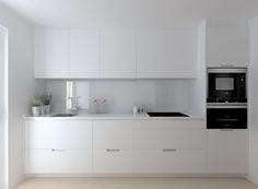 an empty kitchen with white cabinets and appliances