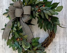 a wreath with green leaves and berries on a wooden background, hanging on the wall