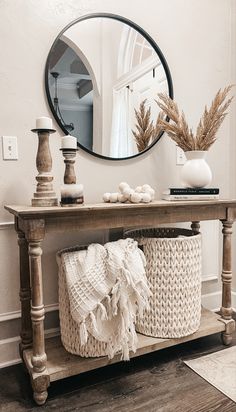 a wooden table topped with baskets under a mirror