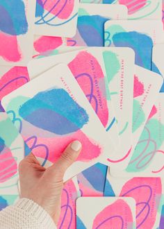 a hand is holding up some stickers with blue and pink designs on them