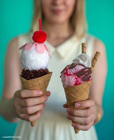 the woman is holding two ice cream cones with toppings on them, both in their hands