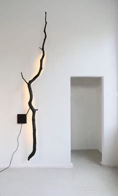 a wall mounted light with a tree branch on it