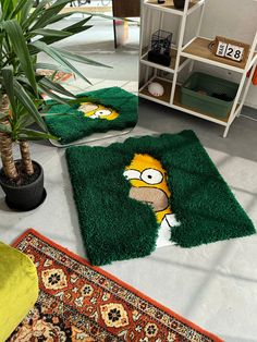 two rugs with the simpsons face on them are sitting in front of a potted plant