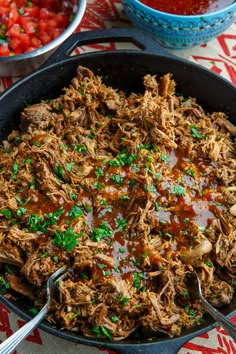 a skillet filled with pulled pork and gravy on top of a table