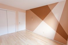 an empty room with wooden floors and walls painted in different shades of orange, brown and white