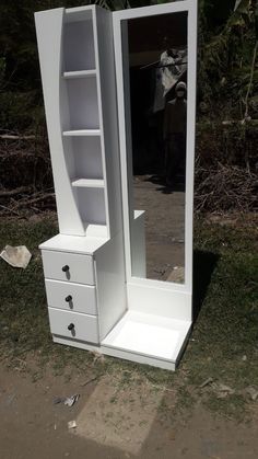 a white dresser and mirror sitting in the grass