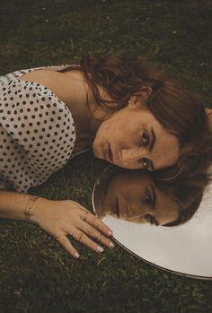 a woman laying on the ground with her reflection in a mirror that is reflecting her face