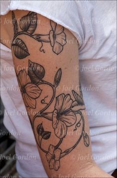 a woman's arm with flowers and leaves tattooed on the side of her arm