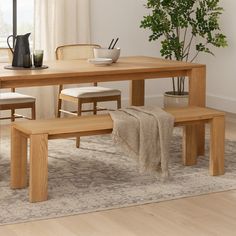 a wooden table and bench in a room with a rug on the floor next to it