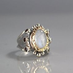 "Moonstone Ring, Garnet Ring, 9K Yellow Gold Hammered Queen Ring in Sterling Silver Band, Gemstone Ring, Antique Style Ring, Chunky Ring This garnet and moonstone ring looks like it was made for a queen. It is ornate but delicate, statement piece but not oversize. The band is adjustbale to any finger size and made of sterling silver set with dark red natural garnet gemstone. The center is a bezel set moonstone gemstone and 9K solid gold, welded on sterling silver, hammered around the moonstone. Unique White Multi-stone Moonstone Ring, White Fusion Style Gemstone Ring, Heirloom Moonstone Gemstone Ring, Unique White Ring With Accent Stones, Unique White Rings With Rose Cut Diamonds, Unique White Rings With Accent Stones, Unique Anniversary Rings With Gemstone Accents, Heirloom Multi-stone Moonstone Ring For Anniversary, White Sapphire Ring With Accent Stones