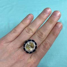 a person's hand holding a ring with a yellow and white diamond in it