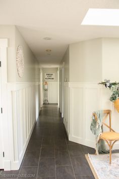 the hallway is clean and ready to be used for decorating with white walls, black tile floors and wood trim