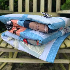 a stack of quilts sitting on top of a wooden chair next to a tree