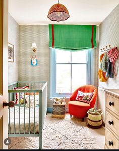 a baby's room with a crib, chair and window