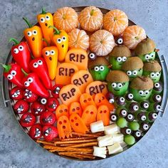 a platter filled with oranges, peppers and other food items that have eyes on them