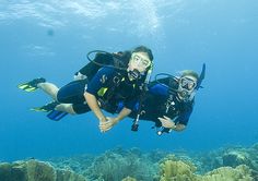 two people are diving in the ocean with scuba gear and equipment on their feet,