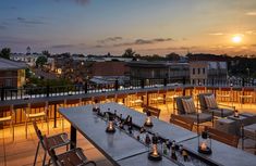 an outdoor dining area overlooking the city at sunset or dawn with lit candles on tables and chairs