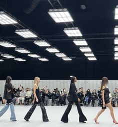 several models walk down the runway in front of an audience wearing black outfits and high heeled shoes