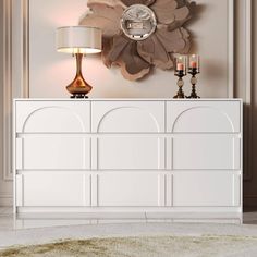 a white dresser sitting in front of a wall with a clock on it's face