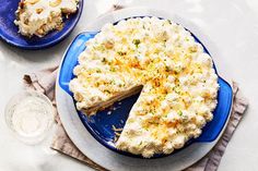 a blue plate topped with a cake covered in white frosting and toppings next to a slice of pie