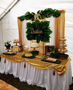 a table topped with lots of desserts under a white tented area covered in gold curtains