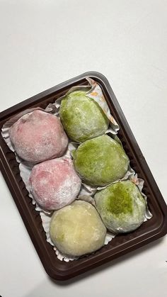 four different colored pastries sitting on top of a tray