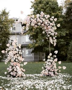 an arch made out of flowers in the middle of a field with white petals on it