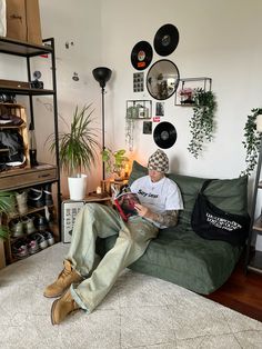 a man sitting on top of a green couch next to a wall filled with records