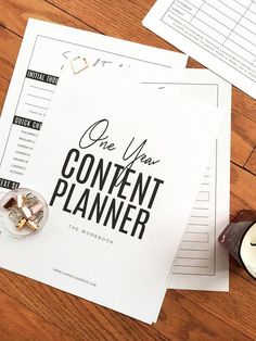 a wooden table topped with lots of paper next to a candle and some papers on top of it