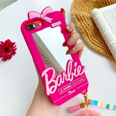 a person holding a pink phone case with the word barbie on it and a bow